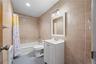 Full tile surround, white vanity, integrated sink, mirrored cabinet, and recessed ceiling lighting