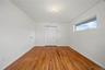 Hardwood flooring, white walls, flush mount ceiling light, horizontal window with roller shade, bi-fold closet doors