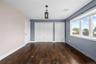 Dark wood-finish flooring, a decorative ceiling light fixture, and a bay window