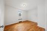 Wood-finish flooring, white painted walls, single window, baseboard heating unit, and ceiling-mounted light fixture