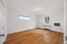 Hardwood flooring, white painted walls, two windows, and a flush mount ceiling light