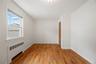 Hardwood flooring, painted white walls, white window trim, white crown molding, and a wood-finish bi-fold door