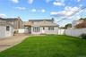 Expansive green lawn, white privacy fencing, paved driveway, detached garage, and a wood deck