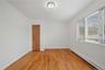 Hardwood flooring, painted walls, louvered closet doors, window with blinds, and ceiling-mounted light fixture