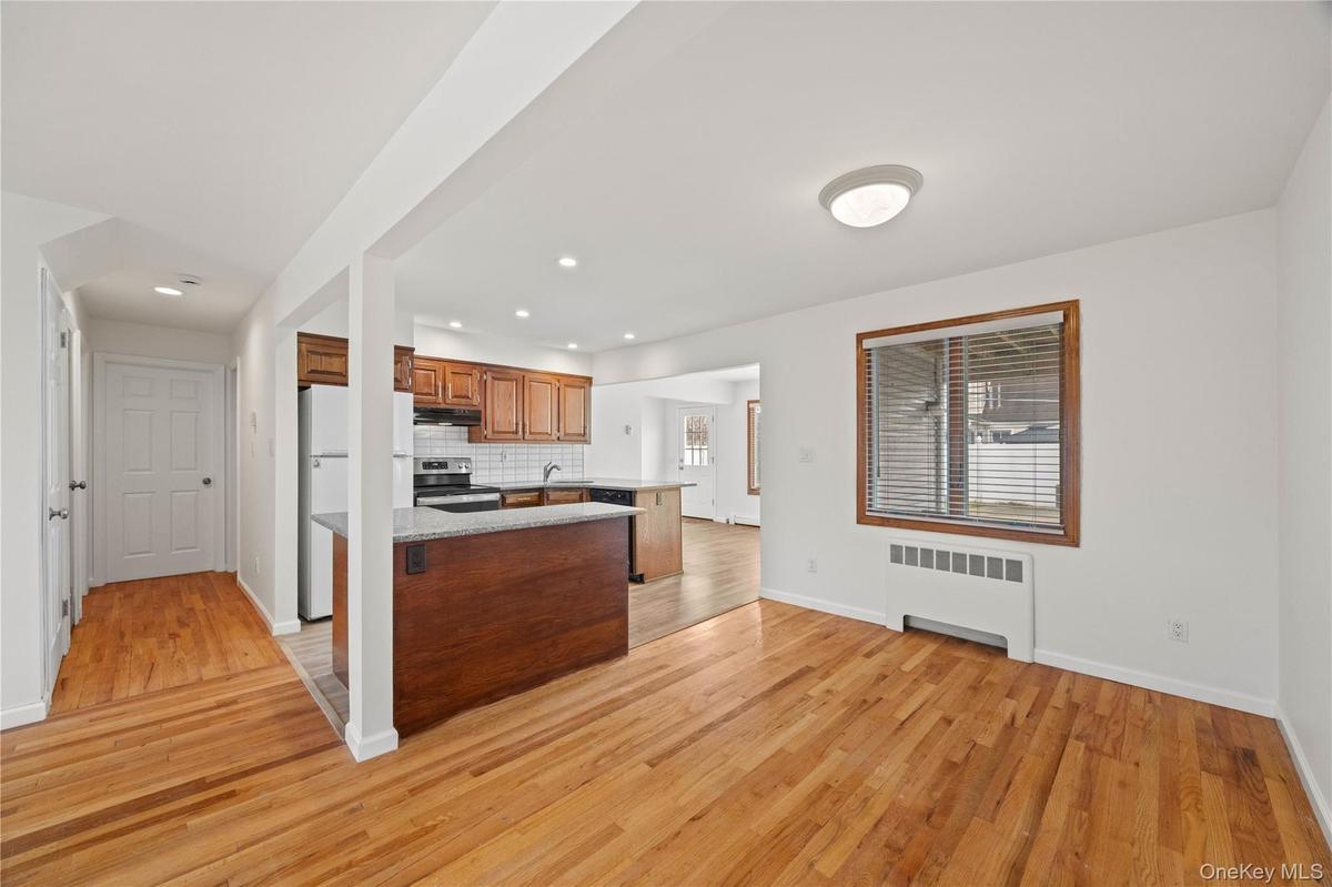 Hardwood flooring, white walls, and a window with blinds
