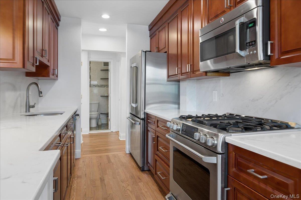 Beautifully designed kitchen features GE Cafe stainless steel appliances and white quartz countertops.