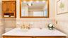 The hallway full bath features a large vanity, stylish accent wall tile, and abundant lighting, creating a bright and beautifully appointed space.