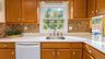 The well-appointed kitchen features stylish accent lighting, a beautiful tile backsplash, and durable tile flooring, combining functionality with time