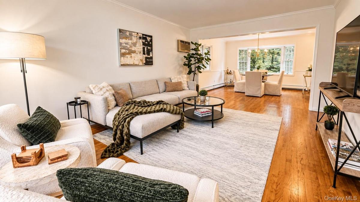 This expansive living room features beautiful hardwood flooring and a seamless open flow into the formal dining area, creating an inviting space for b
