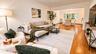 This expansive living room features beautiful hardwood flooring and a seamless open flow into the formal dining area, creating an inviting space for b