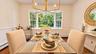This inviting open-concept dining area features beautiful hardwood flooring and an elegant chandelier, creating a warm and stylish setting for memorab