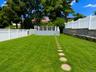 Expansive lawn with stepping stone pathway, white privacy fencing, and a raised composite deck with white railings
