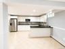 White cabinetry, stainless steel appliances, black countertops, mosaic tile backsplash, and tile flooring