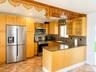 Kitchen featuring wood-finish cabinetry, stainless steel appliances, a mosaic tile backsplash, and a granite-style countertop