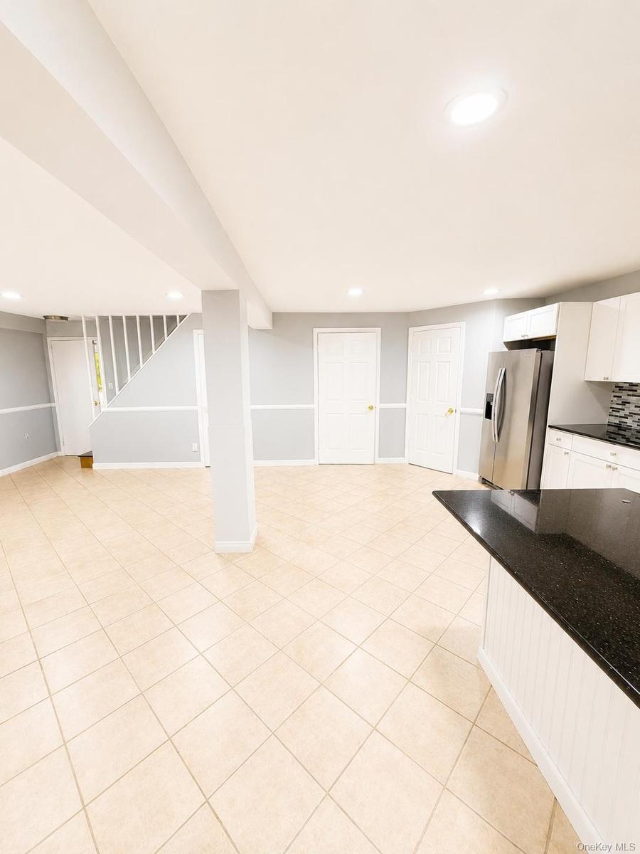Spacious open-concept area featuring tile flooring, recessed lighting, and a kitchen island with a dark countertop