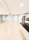 Spacious open-concept area featuring tile flooring, recessed lighting, and a kitchen island with a dark countertop
