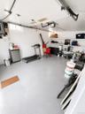 Garage with finished light gray flooring, white walls, and built-in shelving