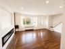 Wood-finish flooring, recessed lighting, and a built-in linear fireplace with a tiled hearth