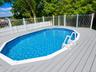Swimming pool featuring a gray composite deck, perimeter safety fencing, and white entry steps