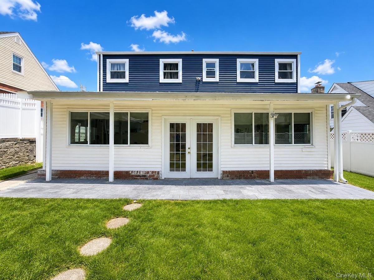 Expansive backyard featuring a stone paver patio, lush green lawn, and stepping stones