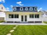 Expansive backyard featuring a stone paver patio, lush green lawn, and stepping stones