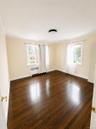 Wood-finish flooring, two windows, radiator, and a flush mount ceiling light fixture