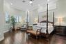 Also on the first floor is a spacious primary suite with high ceilings, wood floors, clerestory windows over the bed, crown molding and an entry door 