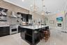 The chefs kitchen features new cabinets, a stone backsplash, pot filler over the gas stove, a large island, and a view into the family room