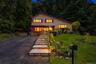 Split-level residence featuring a paved driveway, stone retaining walls, and a multi-level stone walkway.