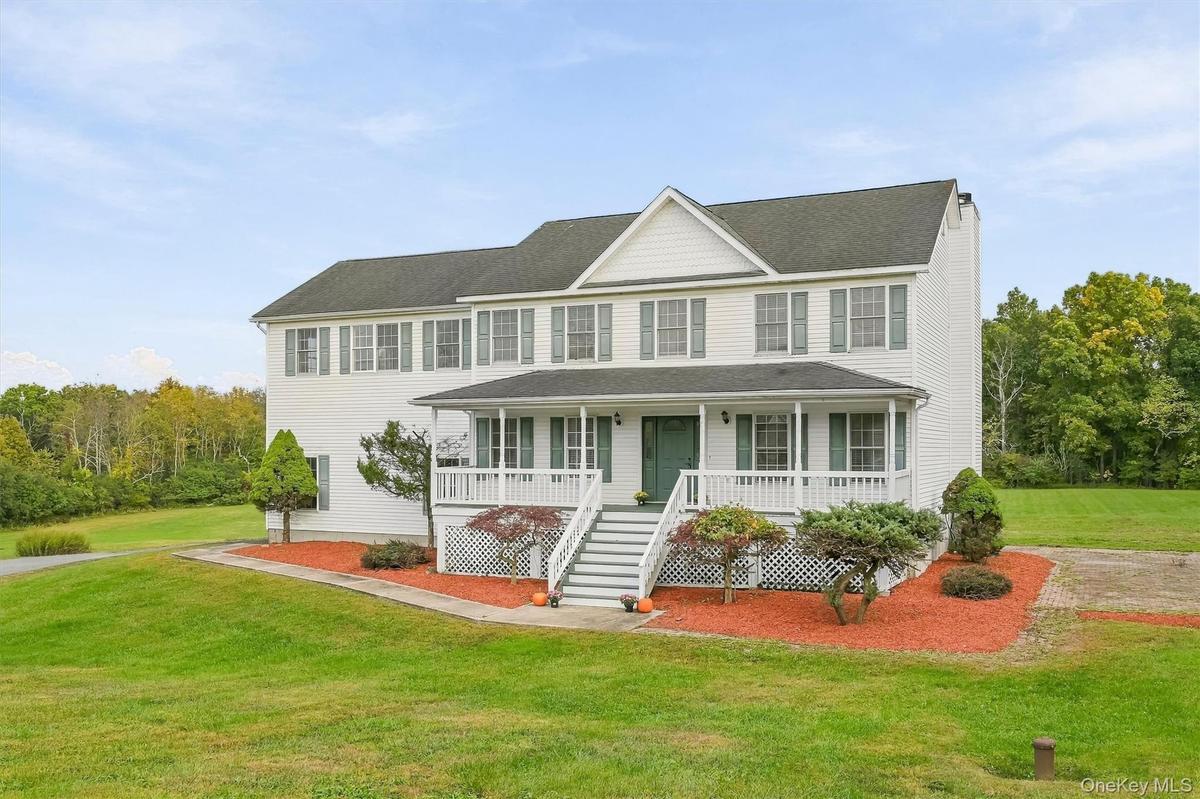 Timeless Colonial charm framed by mature landscaping and a full-length covered porch.
