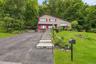 Split-level residence featuring a paved driveway, stone retaining walls, and a tiered stone walkway