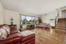 Second level living room featuring wood flooring, and a large  window with a view. Steps lead up to bedroom level or down to recreation room.