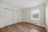 Third bedroom with warm flooring and a full wall of closet space.