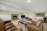 Tile flooring, stone-faced fireplace with hearth, recessed lighting, and window overlooking the backyard.