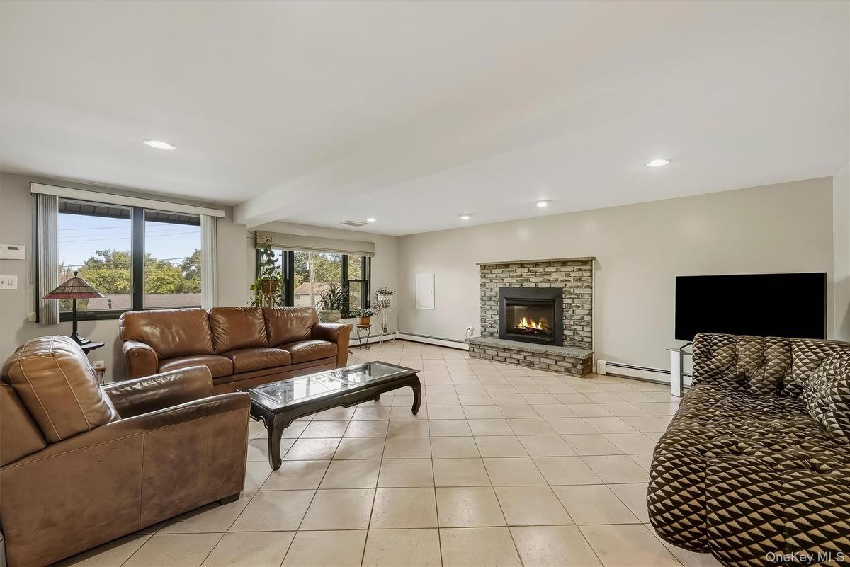 Spacious recreation room featuring tile flooring, a stone-clad fireplace, and recessed lighting