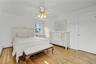 Substantially sized primary bedroom with warm oak flooring and ceiling fan