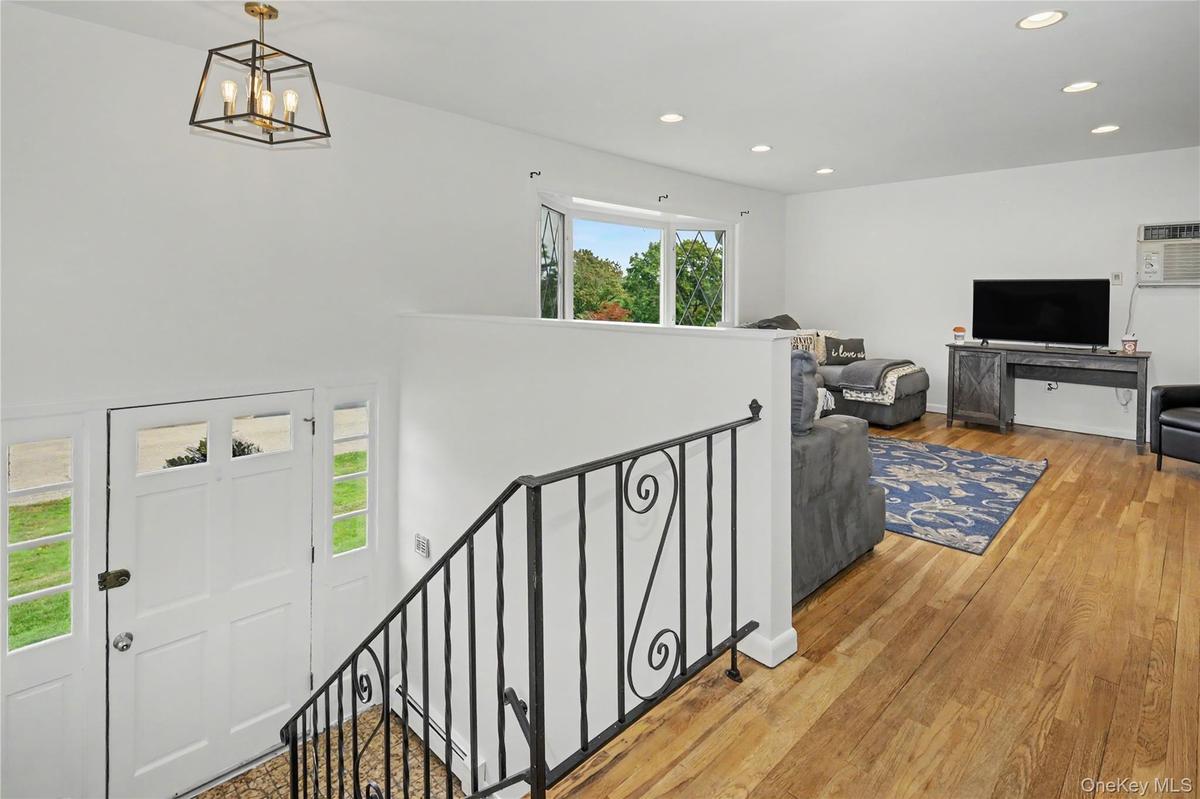 Inviting entranceway leads to living room with wonderful natural light, wood flooring and subtle recessed lighting