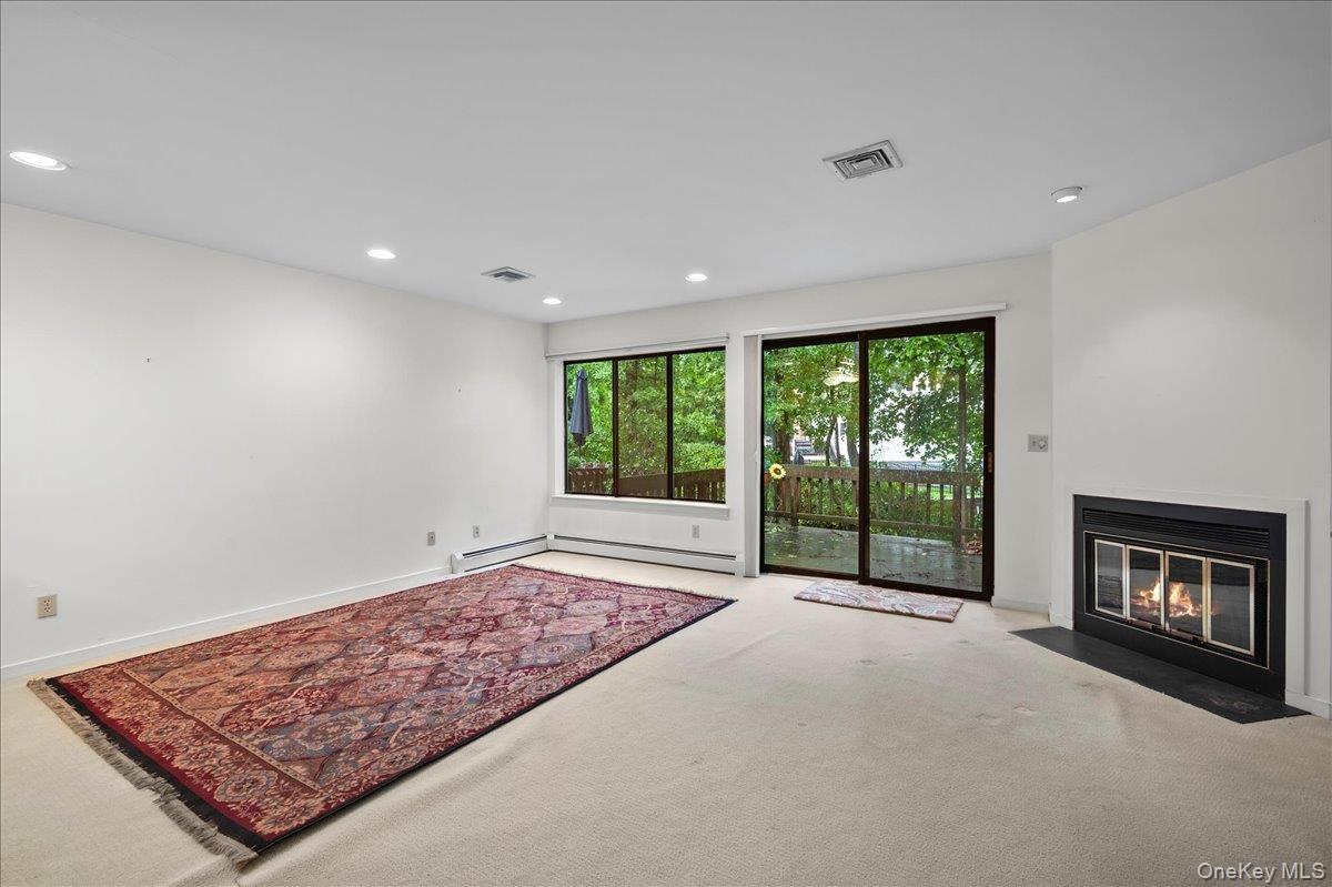 View of the living room looking out to the wood-burning fireplace and glass sliders to the patio