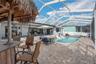 screened outdoor retreat featuring a heated saltwater pool, Tiki bar and spacious pavered deck.