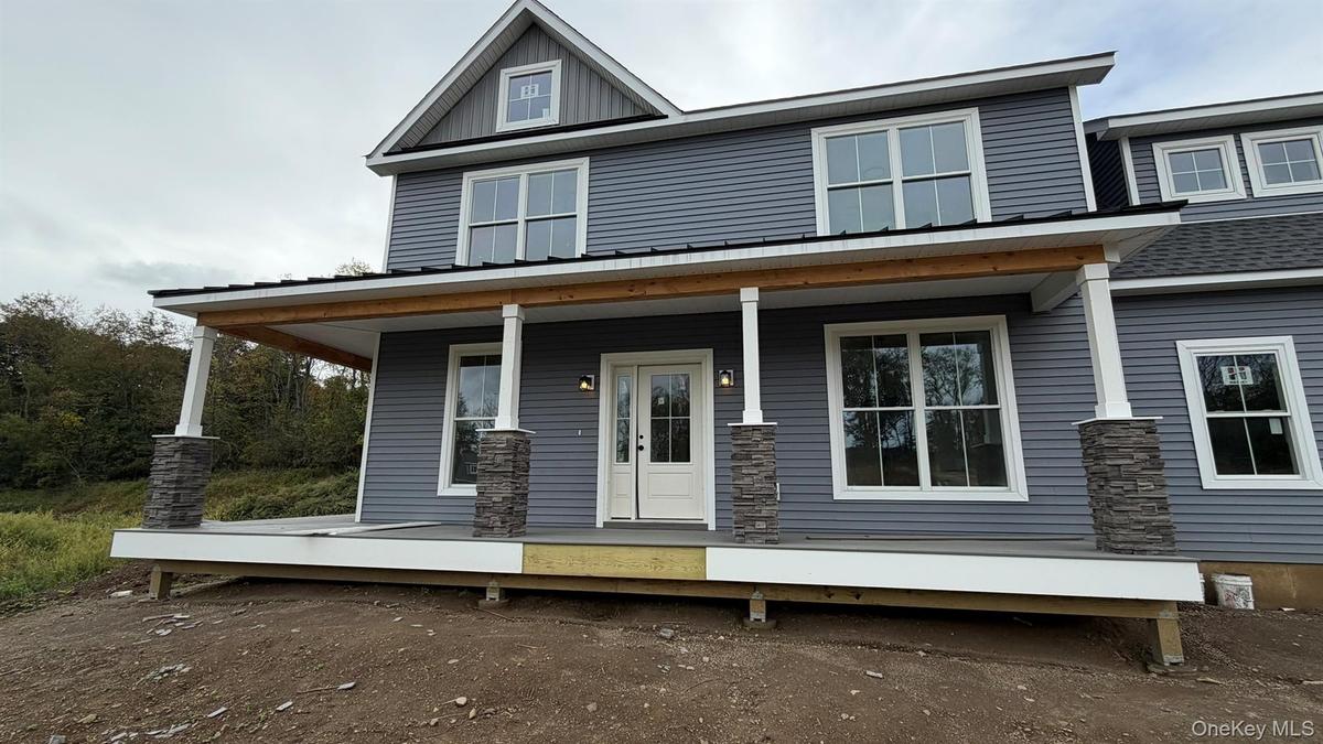Welcome come to the Fennel, featuring blue siding, white trim, a dark shingle roof, a black metal porch roof, and multiple dormer windows.