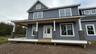 Welcome come to the Fennel, featuring blue siding, white trim, a dark shingle roof, a black metal porch roof, and multiple dormer windows.