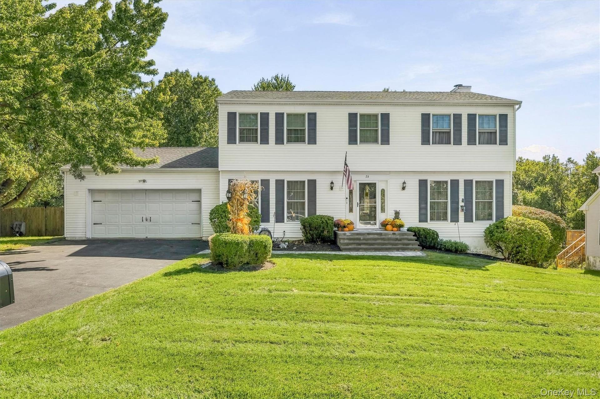 White siding exterior with dark shutters, attached two-car garage, and established front landscaping