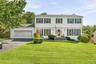 White siding exterior with dark shutters, attached two-car garage, and established front landscaping