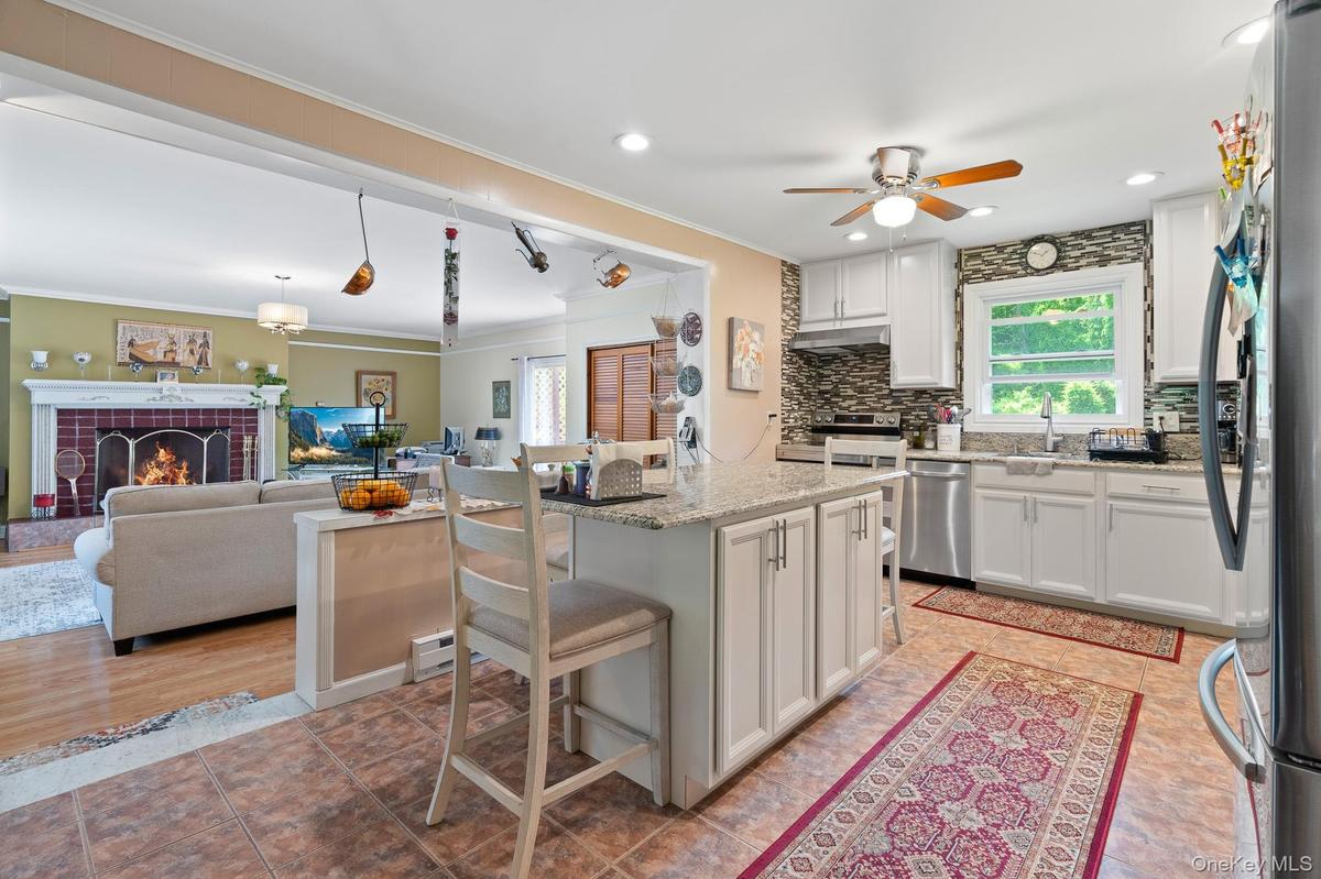Kitchen featuring stainless steel appliances, a kitchen breakfast bar, white cabinetry, a ceiling fan, and ornamental molding