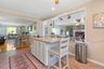 Kitchen with open floor plan, ornamental molding, white cabinets, a brick fireplace, and light stone counters
