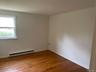 Spare room featuring a baseboard heating unit, wood finished floors, and baseboards