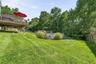 Elevated wood deck, expansive green lawn, above-ground pool, pool deck, and mature trees