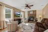 Stone-faced fireplace with a wood mantel, wood-finish flooring, and a ceiling fan