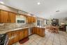 Kitchen featuring wood cabinetry, light-toned stone countertops, and a tiled backsplash