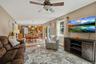 Open-concept living space featuring a ceiling fan, wall-mounted television, and wood-finish media console
